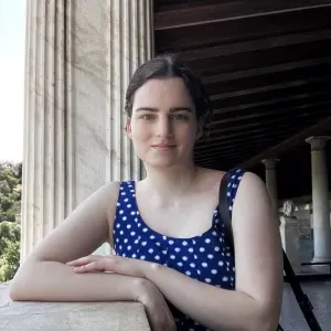  Emma Agudelo ‘24 with a blue top leaning against a wall with classical columns behind